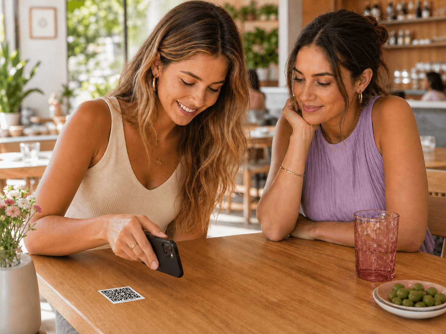 Dos clientes escanean la pegatina QR colocada en la esquina de su mesa.