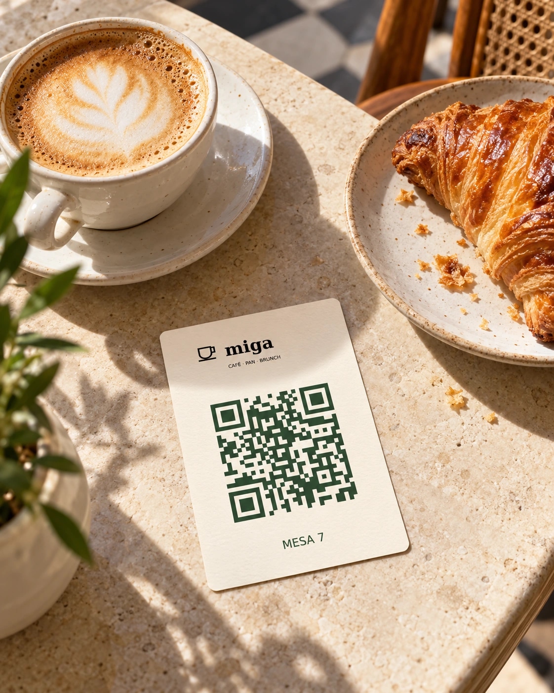 Mesa de cafetería con un QR de Miga junto al café y un cruasán